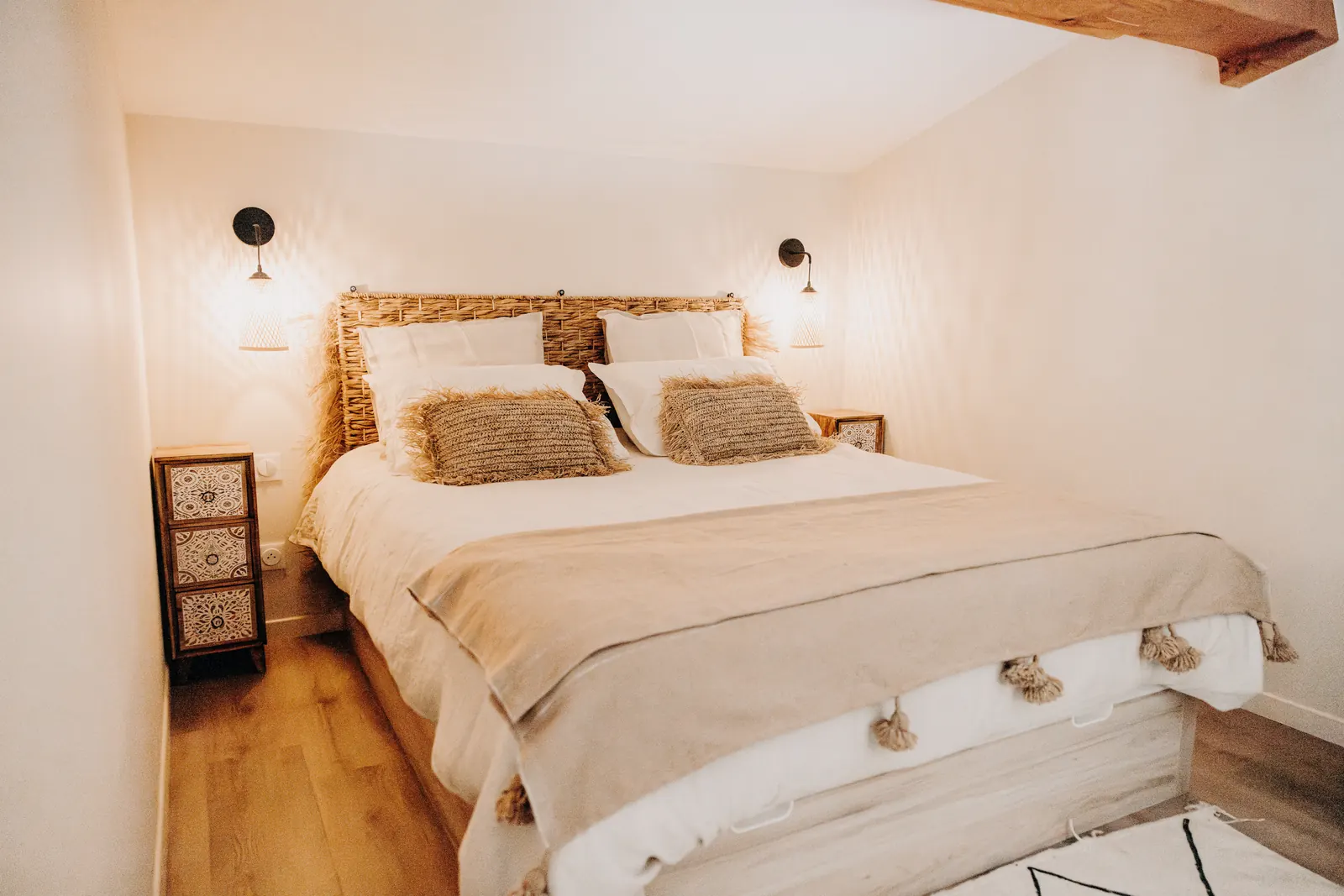 La chambre est de l'étage : lit double, tête de lit tressée et coussins en fibres naturelles