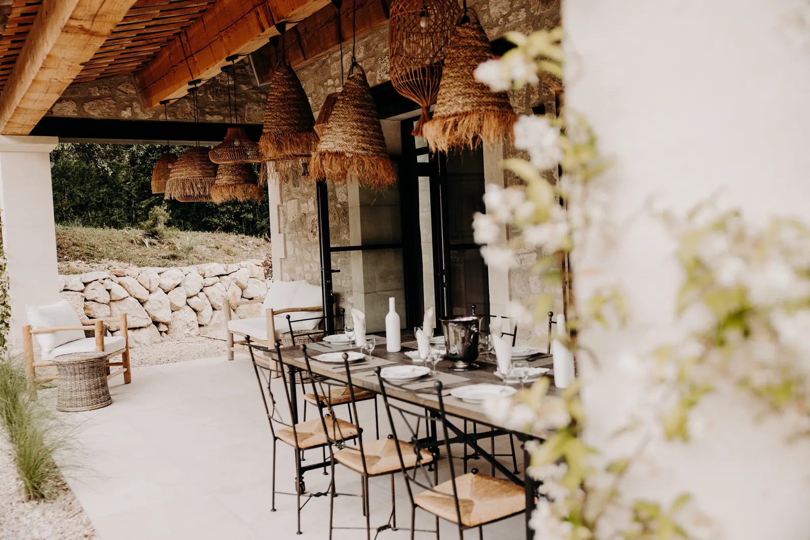 La grande table dressée sous la terrasse couverte, entre jasmin et murets de pierre