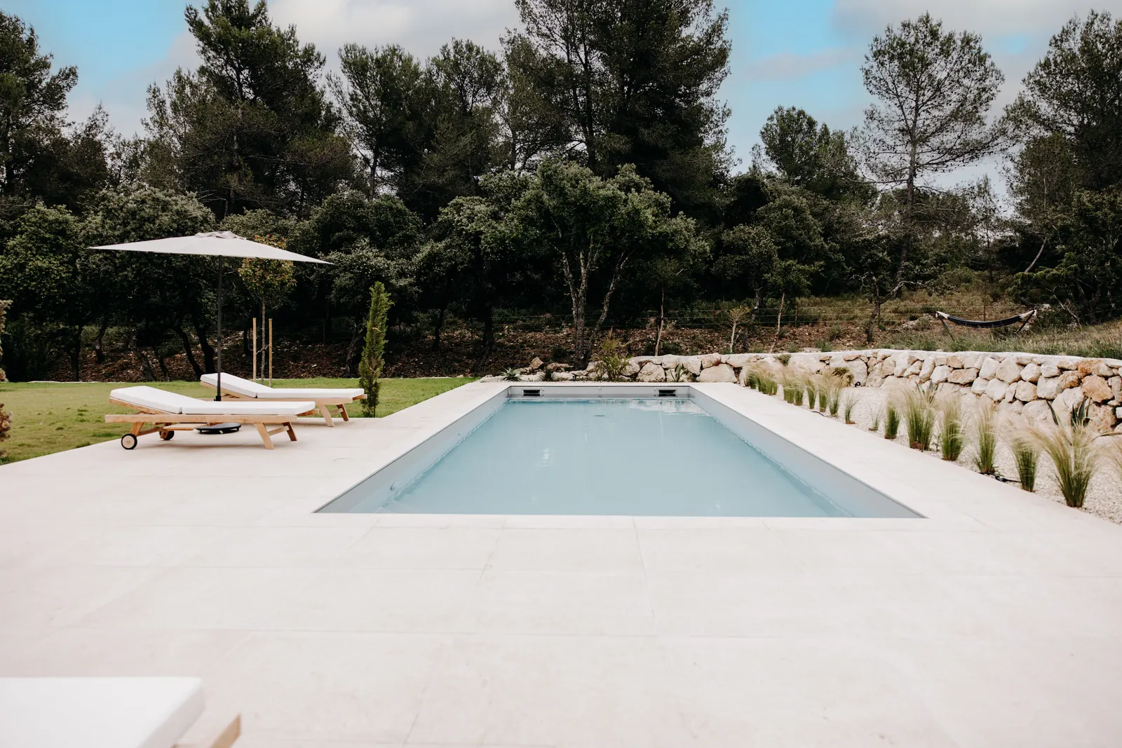 La piscine au sel et ses transats, au milieu du jardin, à Eygalières