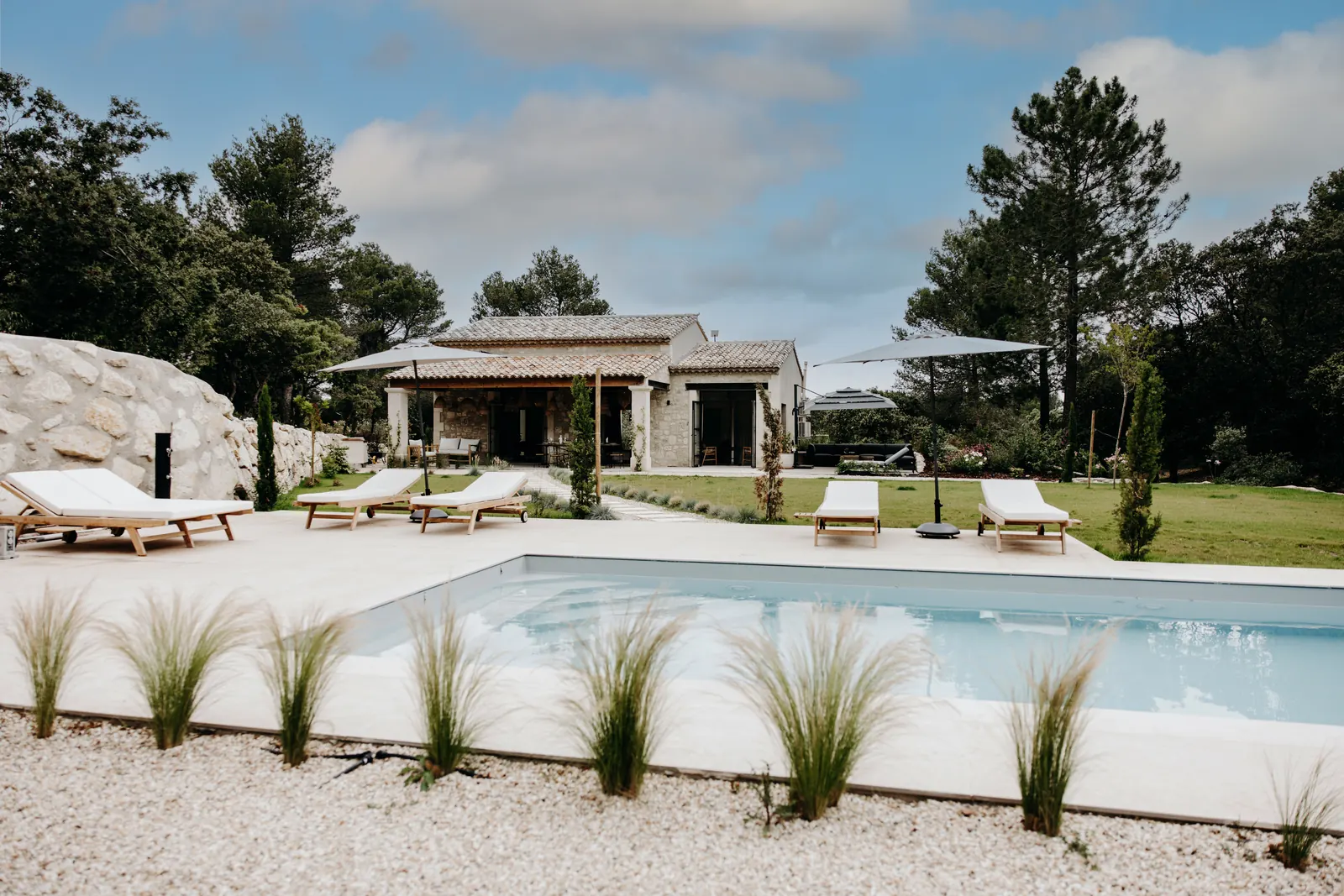 La piscine au sel au premier plan, la maison en pierre au fond du jardin, à Eygalières