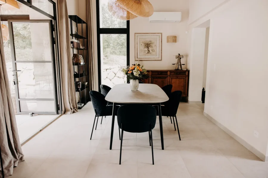 La salle à manger du séjour : table ovale, chaises noires et bouquet de fleurs