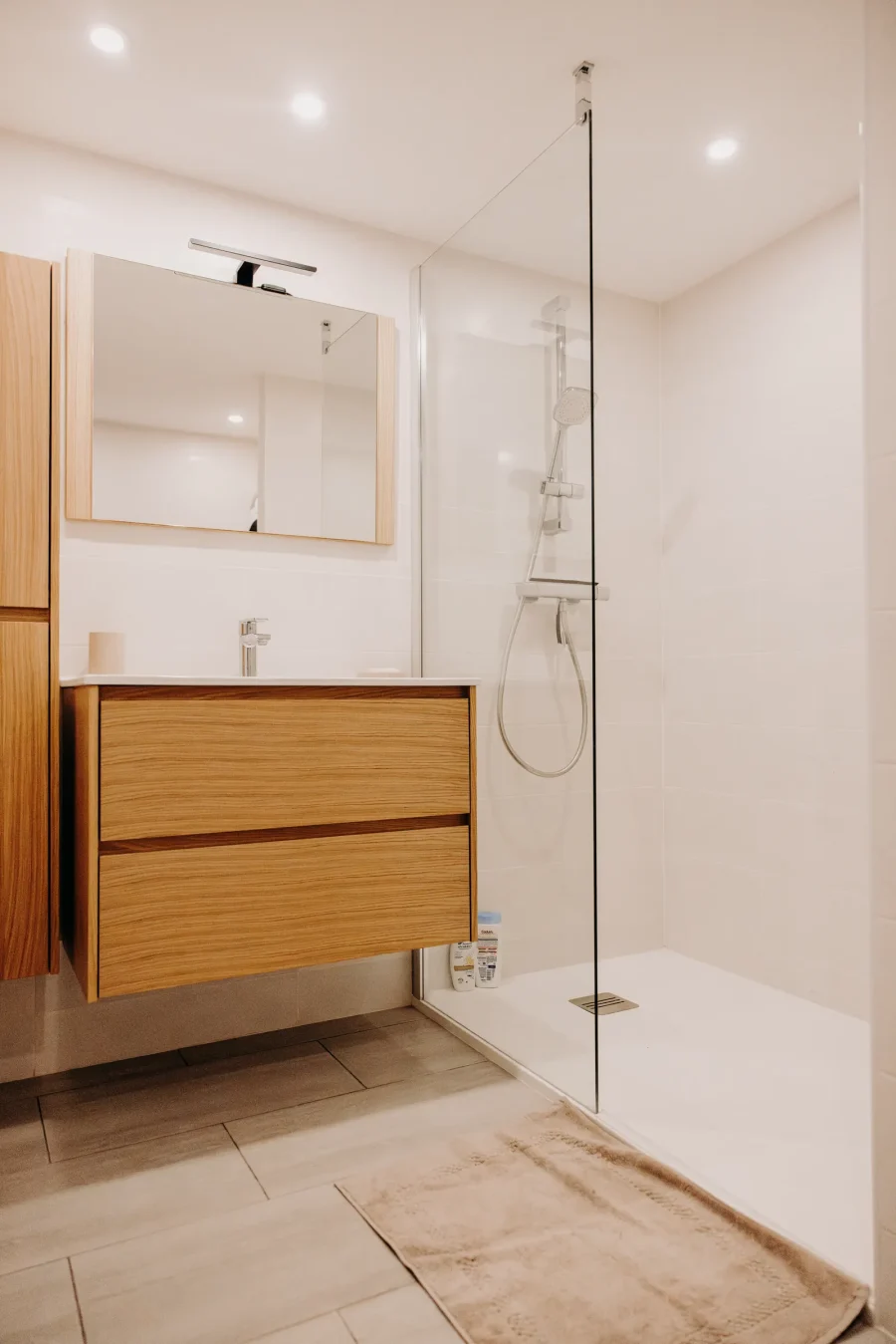 La salle de bain du rez-de-jardin : meuble en bois clair et douche vitrée