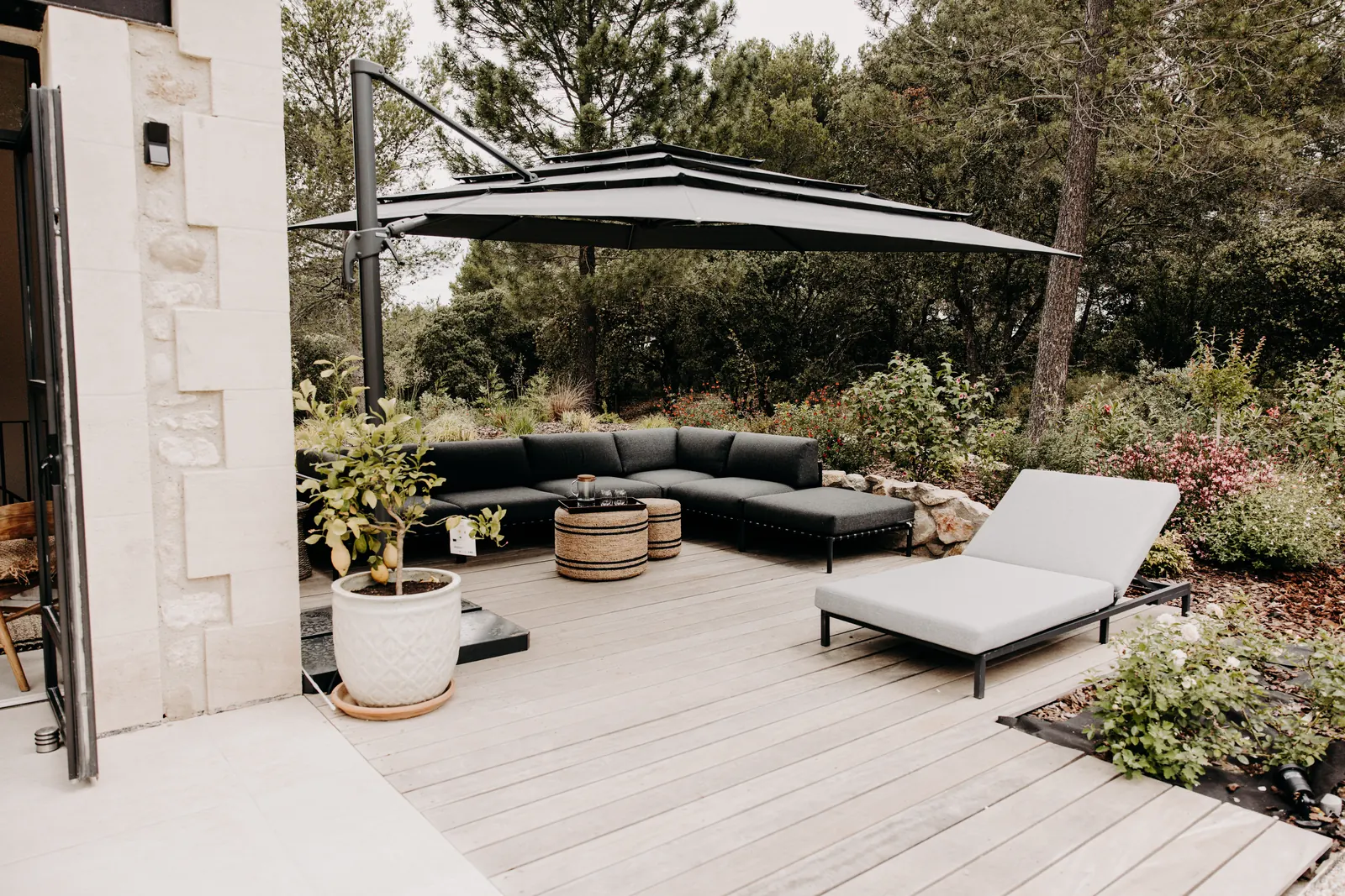 Le salon d'extérieur de la terrasse est : canapé d'angle, bain de soleil et parasol