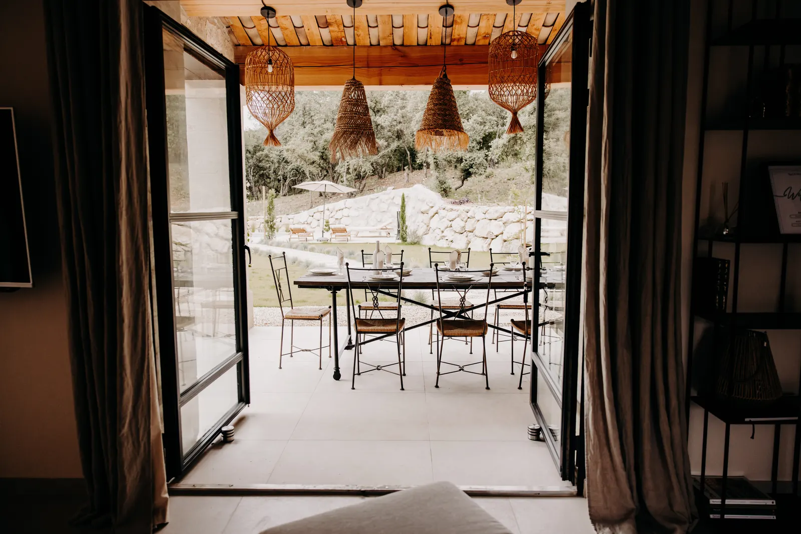 Depuis le séjour, les portes-fenêtres ouvertes sur la terrasse couverte et sa grande table